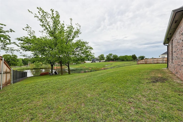 view of yard featuring a water view and a fenced backyard