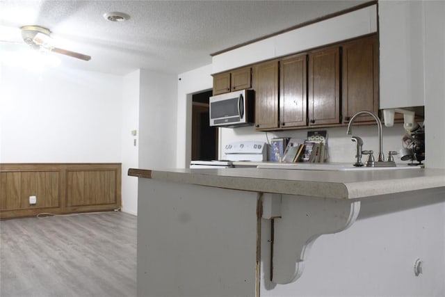 107 S 10th St, Davis, OK 73030 - kitchen with stainless steel microwave, white range oven, a textured ceiling, ceiling fan, and light wood finished floors