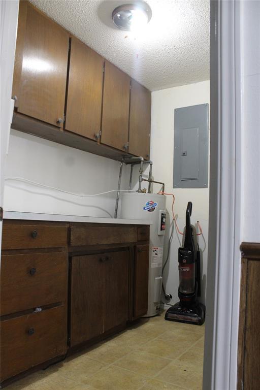 107 S 10th St, Davis, OK 73030 - laundry area featuring electric panel, electric water heater, and a textured ceiling