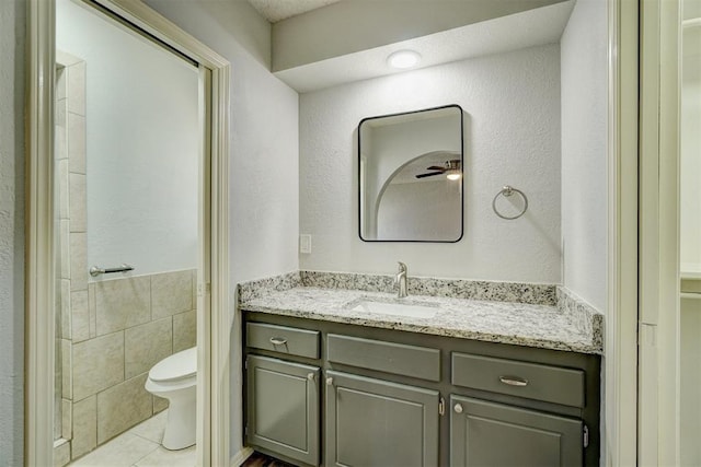 bathroom with tile walls, tile patterned flooring, vanity, a wainscoted wall, and toilet
