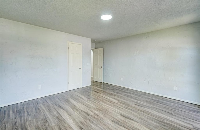 unfurnished room featuring baseboards, a textured ceiling, and wood finished floors
