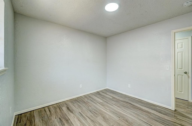 spare room with baseboards, a textured ceiling, and wood finished floors