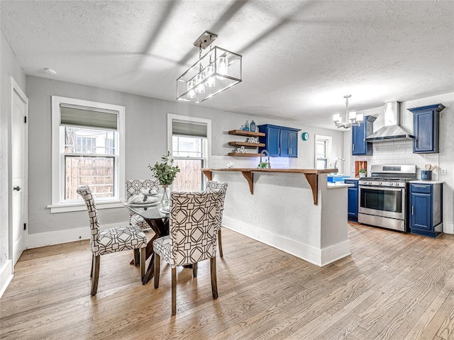 725 NE 15th St, Oklahoma City, OK 73104 - dining area featuring a textured ceiling, light wood-style floors, a notable chandelier, and baseboards