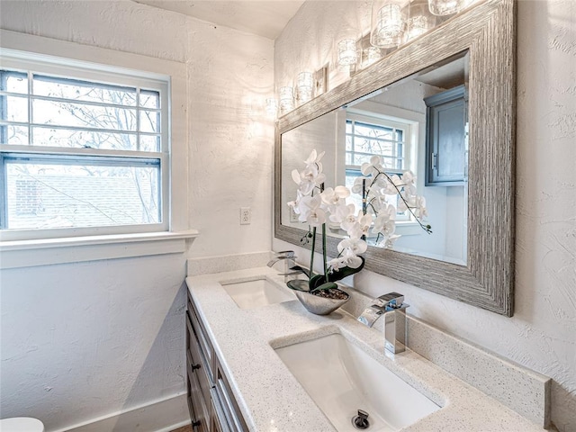 725 NE 15th St, Oklahoma City, OK 73104 - full bathroom featuring double vanity, a textured wall, and a sink