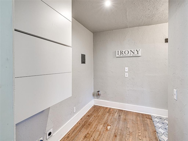 725 NE 15th St, Oklahoma City, OK 73104 - laundry area with baseboards, laundry area, wood-type flooring, and a textured wall