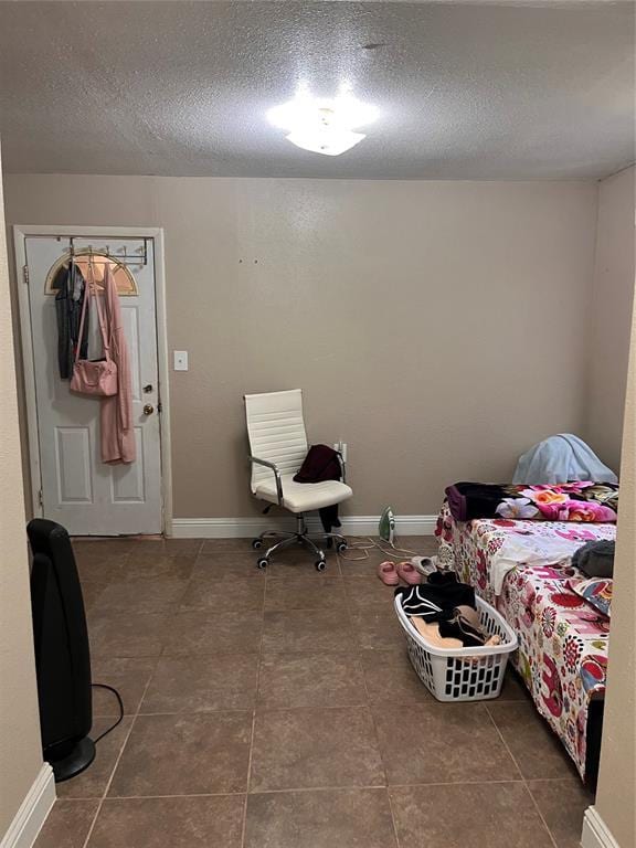 607 E Liveoak St, Altus, OK 73521 - tiled bedroom with a textured ceiling and baseboards