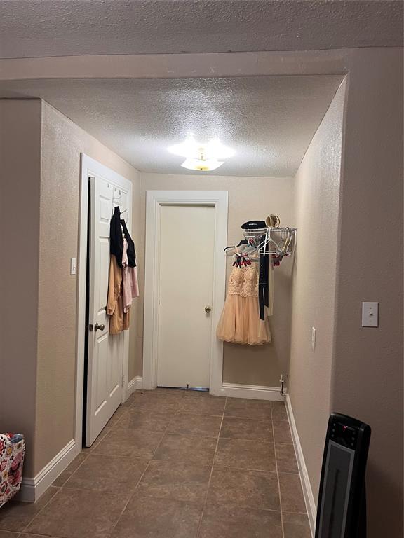 607 E Liveoak St, Altus, OK 73521 - doorway featuring a textured ceiling, tile patterned floors, and baseboards