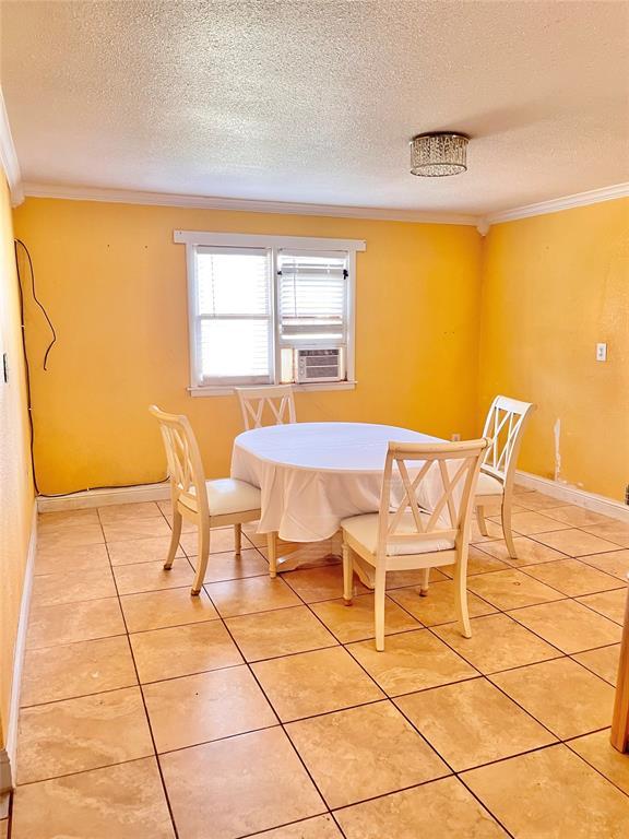 607 E Liveoak St, Altus, OK 73521 - dining room with a textured ceiling, crown molding, and light tile patterned floors
