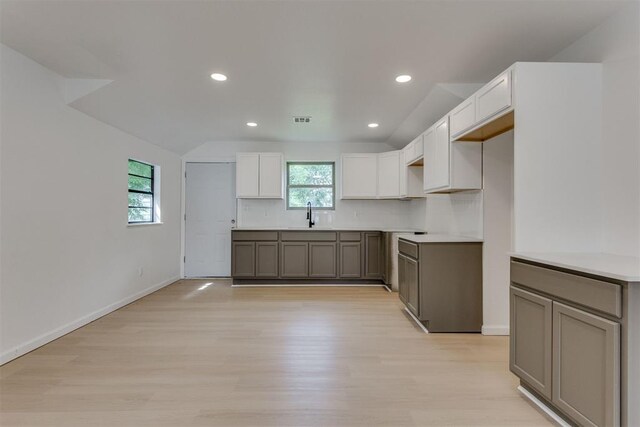 1437 SW 34th St, Oklahoma City, OK 73119 - kitchen featuring white cabinets, a sink, baseboards, light wood-type flooring, and backsplash