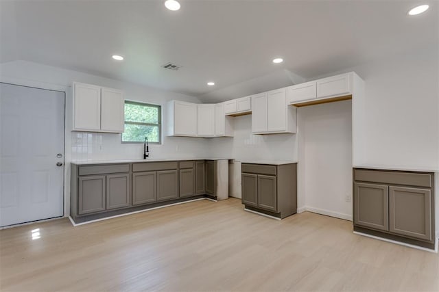 1437 SW 34th St, Oklahoma City, OK 73119 - kitchen featuring visible vents, a sink, light wood-style flooring, and decorative backsplash