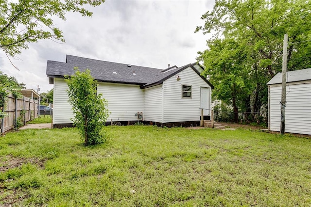1437 SW 34th St, Oklahoma City, OK 73119 - back of house with a yard, fence, a shingled roof, and entry steps