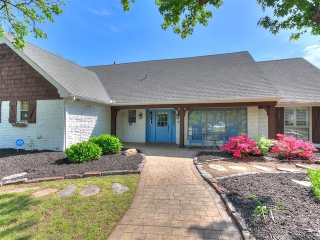 12112 Blue Sage Rd, Oklahoma City, OK 73120 - view of exterior entry with brick siding, a shingled roof, and a porch