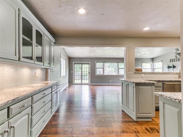 12112 Blue Sage Rd, Oklahoma City, OK 73120 - kitchen featuring decorative backsplash, glass insert cabinets, open floor plan, dark wood-style floors, and dishwasher