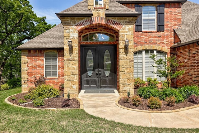 2051 Vaquero Ct, Edmond, OK 73034 - entrance to property featuring brick siding, stone siding, a shingled roof, and french doors