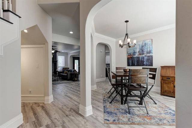 2051 Vaquero Ct, Edmond, OK 73034 - dining area with arched walkways, light wood-type flooring, baseboards, an inviting chandelier, and ornamental molding