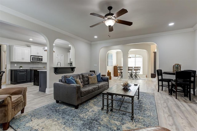 2051 Vaquero Ct, Edmond, OK 73034 - living area featuring arched walkways, light wood-type flooring, crown molding, and ceiling fan
