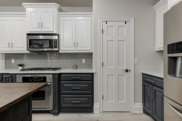 2051 Vaquero Ct, Edmond, OK 73034 - kitchen with white cabinets, light wood-style floors, backsplash, and appliances with stainless steel finishes