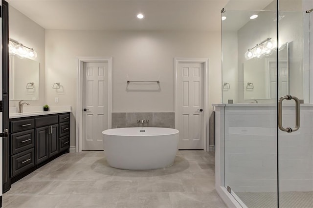 2051 Vaquero Ct, Edmond, OK 73034 - bathroom with recessed lighting, a shower stall, a freestanding bath, vanity, and tile walls