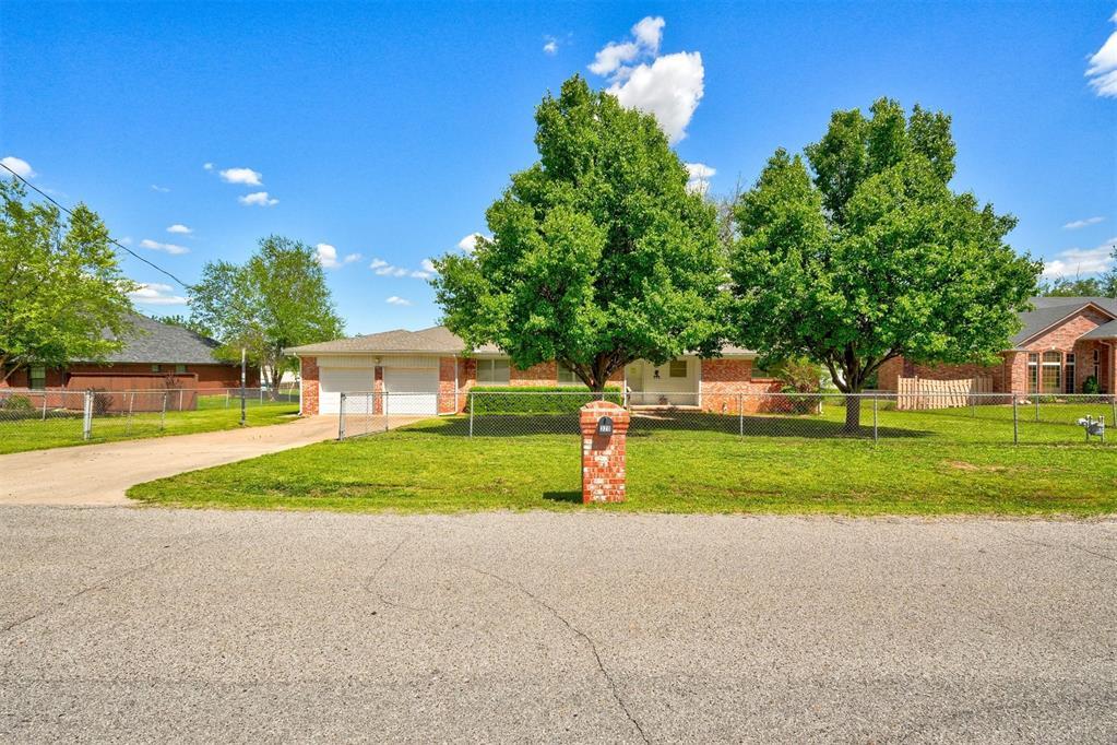 view of front of home featuring a fenced front yard, brick siding, a garage, driveway, and a front lawn
