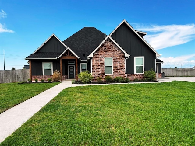 craftsman-style house featuring board and batten siding, brick siding, a front yard, and fence