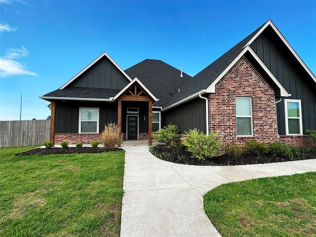 craftsman-style house with a front lawn, board and batten siding, fence, brick siding, and roof with shingles