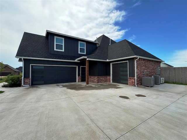 view of front of property with concrete driveway, fence, brick siding, a shingled roof, and board and batten siding