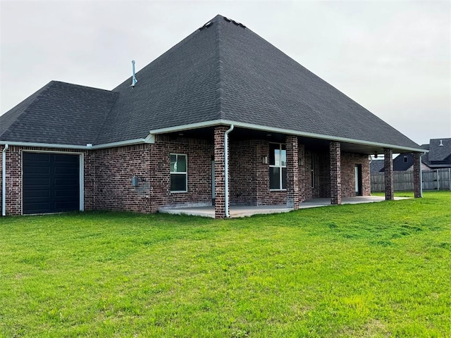 back of house with brick siding, a patio area, a lawn, and fence