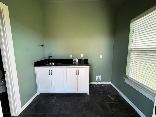 washroom featuring a healthy amount of sunlight, baseboards, and a sink