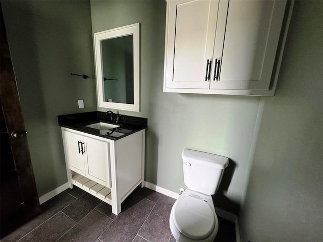 bathroom featuring baseboards, vanity, and toilet