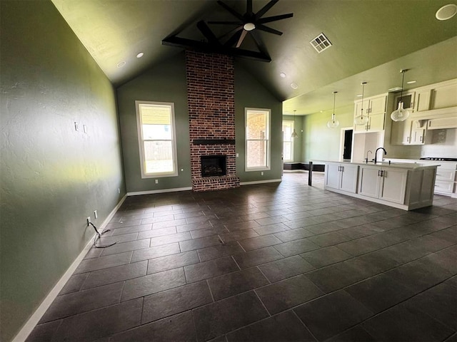 unfurnished living room with baseboards, plenty of natural light, visible vents, and high vaulted ceiling