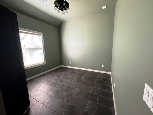 unfurnished room with lofted ceiling, visible vents, baseboards, and dark tile patterned flooring