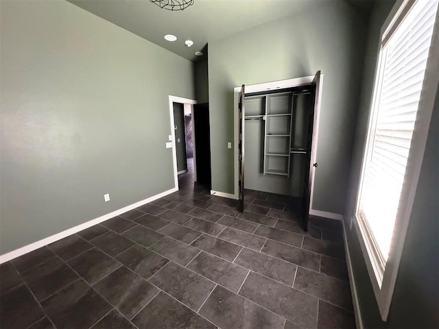 unfurnished bedroom featuring dark tile patterned flooring and baseboards