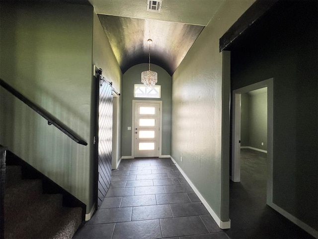 entrance foyer with vaulted ceiling, baseboards, visible vents, stairway, and dark tile patterned flooring