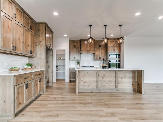 kitchen with light countertops, appliances with stainless steel finishes, light wood-style flooring, and backsplash