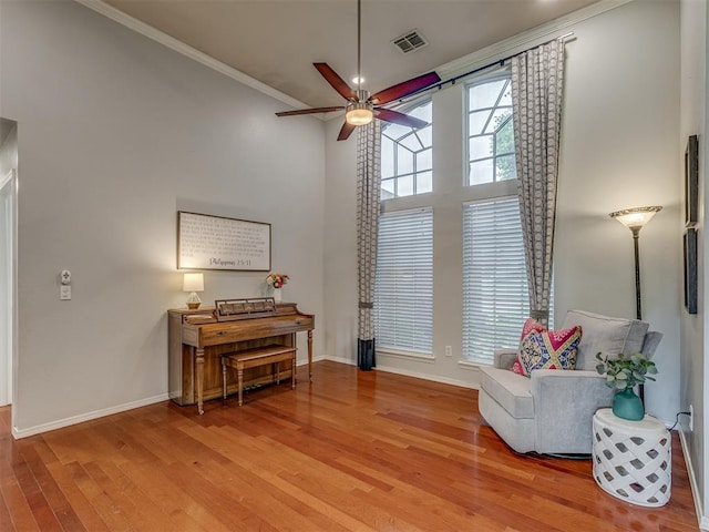 living area with crown molding, a towering ceiling, wood finished floors, and baseboards
