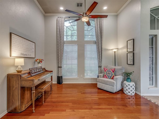 living area featuring ornamental molding, a ceiling fan, and wood finished floors