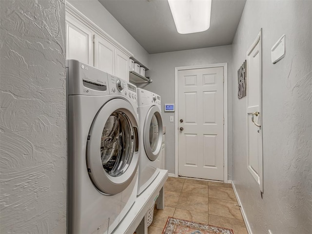 clothes washing area featuring light tile patterned flooring, independent washer and dryer, cabinet space, and baseboards