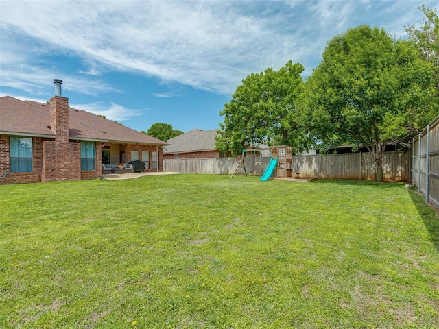 view of yard featuring a patio, a fenced backyard, and a playground