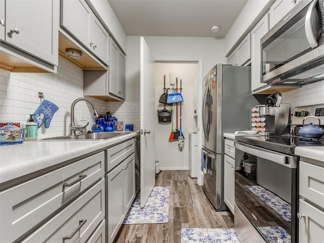 kitchen with light countertops, appliances with stainless steel finishes, wood finished floors, and gray cabinetry