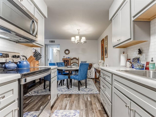 kitchen featuring visible vents, appliances with stainless steel finishes, backsplash, and an inviting chandelier