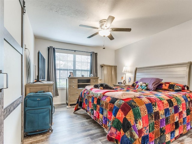 bedroom featuring a ceiling fan, baseboards, wood finished floors, and a textured ceiling