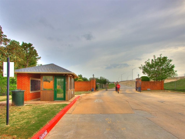 view of road featuring curbs, a gated entry, a gate, street lights, and traffic signs