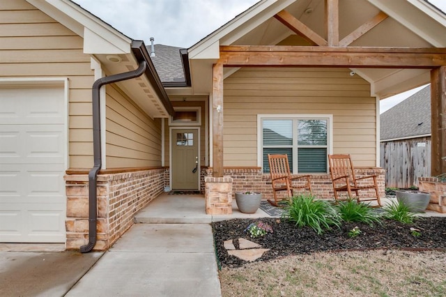 11200 SW 32nd St, Yukon, OK 73099 - view of exterior entry with an attached garage, a porch, brick siding, and a shingled roof