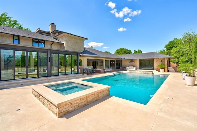 outdoor pool with an in ground hot tub and a patio area