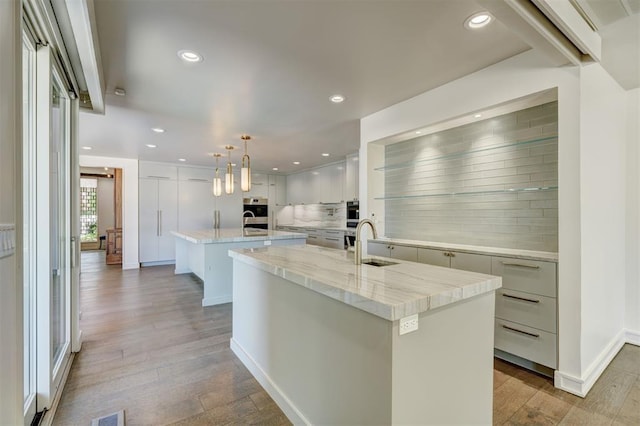 kitchen featuring recessed lighting, a large island, decorative backsplash, and a sink