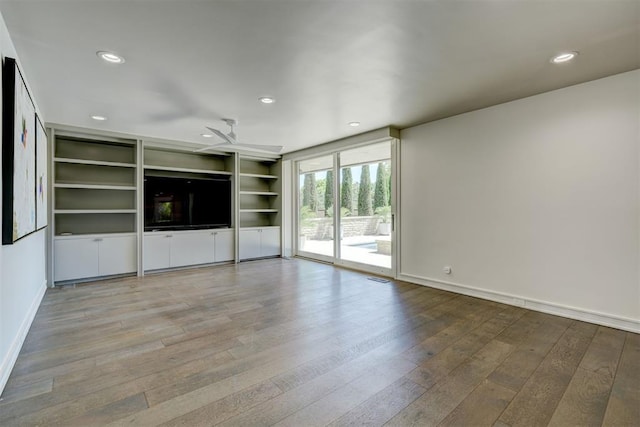 unfurnished living room with baseboards, hardwood / wood-style flooring, and recessed lighting