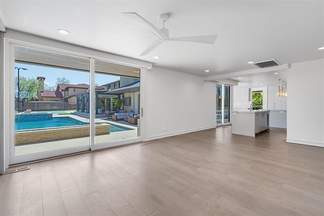 unfurnished living room with a ceiling fan, visible vents, wood finished floors, and recessed lighting