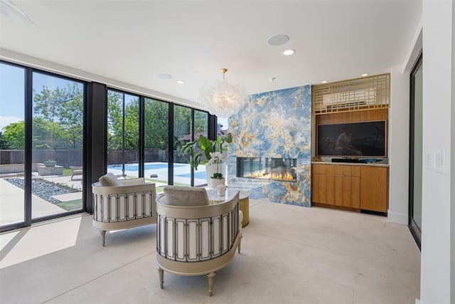 living area with an inviting chandelier, recessed lighting, concrete flooring, and a fireplace