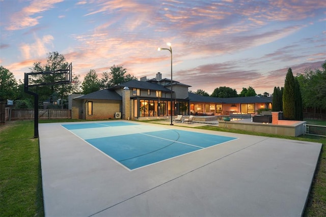 view of sport court with a lawn, fence, and basketball court