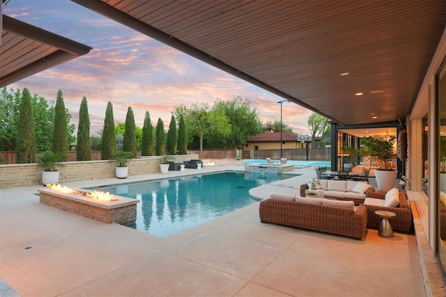 pool at dusk with an outdoor living space with a fire pit, a fenced in pool, a fenced backyard, an in ground hot tub, and a patio area